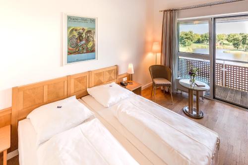 a bedroom with a bed and a desk and a window at Golfhotel & Restaurant Lindenhof in Bad Vilbel