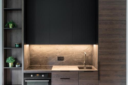 a kitchen with a sink and black cabinets at Modern boutique apartment in the city center in Druskininkai
