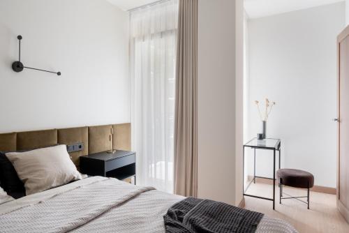 a bedroom with a bed and a chair and a window at Modern boutique apartment in the city center in Druskininkai