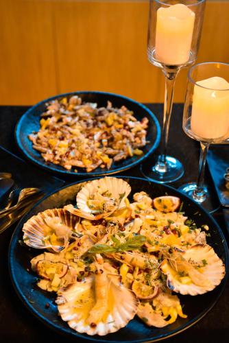 two plates of food on a table with glasses of wine at Illyrian Boutique Hotel in Sarandë