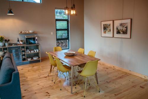 a dining room with a wooden table and yellow chairs at Opstal Stay in Rawsonville