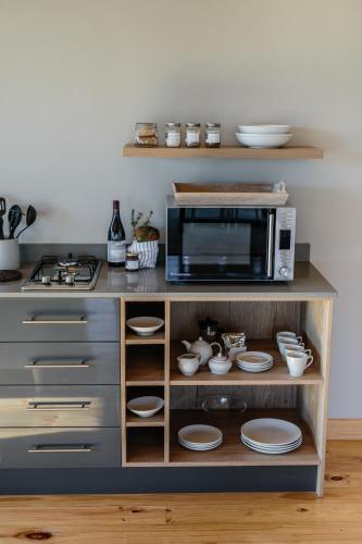 a kitchen with a microwave and plates on a shelf at Opstal Stay in Rawsonville