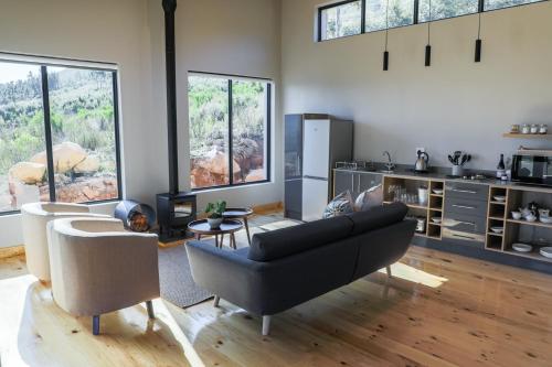 a living room with a couch and some windows at Opstal Stay in Rawsonville