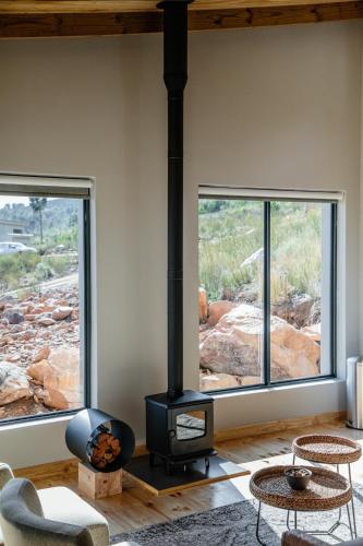 a living room with a stove and two windows at Opstal Stay in Rawsonville