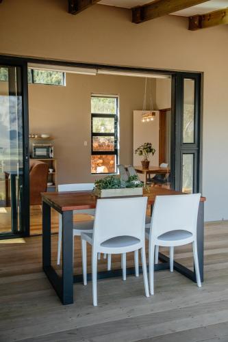a dining room with a table and two white chairs at Opstal Stay in Rawsonville