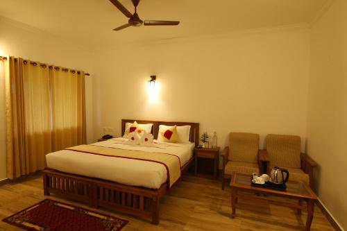 a bedroom with a large bed and two chairs at Dew Drops Farm Resorts in Munnar