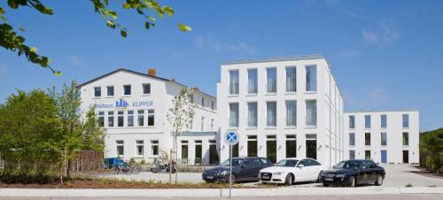 three cars parked in front of a white building at Jugendhaus Klipper Norderney in Norderney