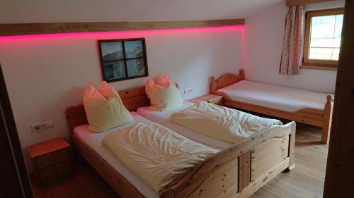 two beds in a room with pink lighting at Haus Joelblick und Haus Oberadelsber in Oberau