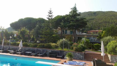 a swimming pool with chairs and a house in the background at Residence la Vignetta in Varazze