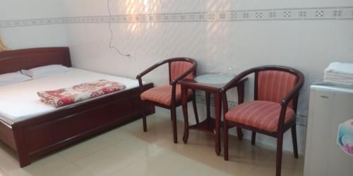 a bedroom with a bed and two chairs and a table at Khách sạn Kim Phụng Ngân in Can Tho