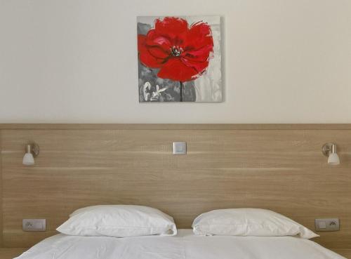 a bed with a wooden head board with a red flower painting at Hôtel de la Citadelle in Sisteron