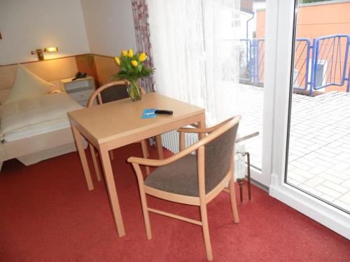 a small table and chair with a vase of flowers at Hotel Phönix in Rastatt