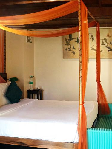 a bed with an orange canopy in a bedroom at Munjoh Ocean Resort - Private Beachfront Luxury Retreat in Havelock in Havelock Island