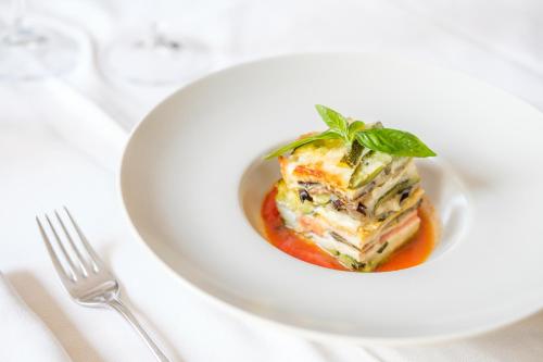 a white plate with a dish of food on a table at Wine Hotel San Giacomo Activity & Wellness in Paderno del Grappa