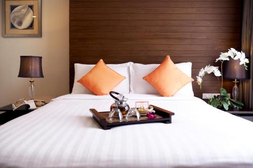 a bedroom with a white bed with a wooden headboard at FuramaXclusive Sathorn, Bangkok in Bangkok