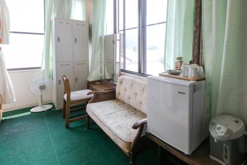 a room with a couch and a refrigerator and a window at Travellersdou Kirinya in Uji