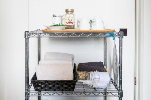 a metal shelf with towels and other items on it at Travellersdou Kirinya in Uji