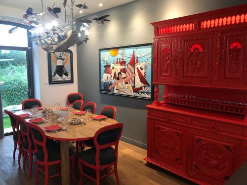 a dining room with a table and a large red cabinet at Le Clos de la Pointe Saint-Mathieu in Plougonvelin