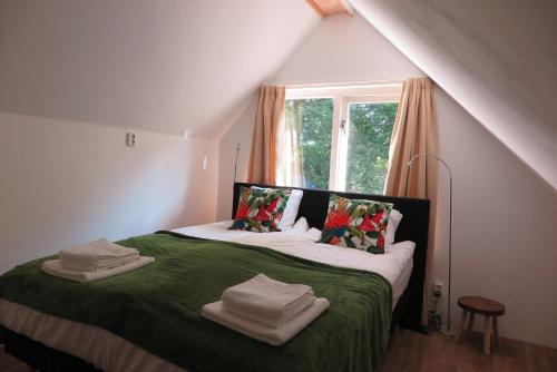 a bedroom with a bed with green sheets and a window at Het Kunstenaarshuis in Kamperland