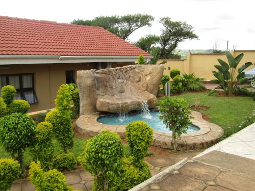 a small pool with a fountain in a yard at Open House Boutique in Manzini