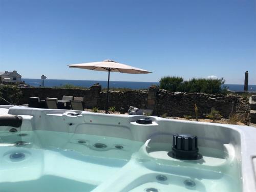 a jacuzzi tub with an umbrella and the ocean at Le Clos de la Pointe Saint-Mathieu in Plougonvelin