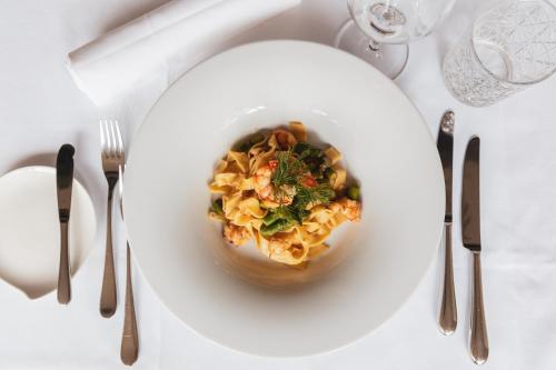 a white plate of pasta on a table with silverware at Feldmilla Design Hotel - Wellness & SPA in Campo Tures