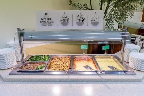 a buffet with several trays of food on a counter at Medical SPA "Eglės sanatorija" Comfort Druskininkai in Druskininkai