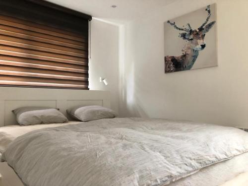 een slaapkamer met een bed en een foto van een hert aan de muur bij Les terrasses de Malmedy duplex 428 in Malmedy