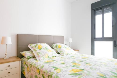 1 dormitorio con 1 cama con sábanas florales y ventana en Apartamento Málaga Litoral Beach II, en Málaga