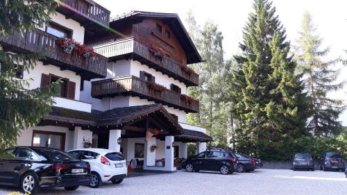 a building with cars parked in a parking lot at Hotel Principe in Cortina dʼAmpezzo