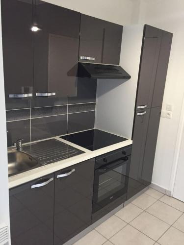 a black kitchen with a sink and a stove at Résidence Studio Grand Luxe Wifi parking privé in Vaulx-en-Velin