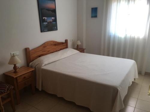 1 dormitorio con cama blanca y ventana en EVA & TRAVEL - Marcel Riumar Apartamento, en Riumar