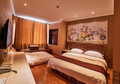 a bedroom with two beds and a painting on the wall at Zhangye Liangmao Hotel in Zhangye