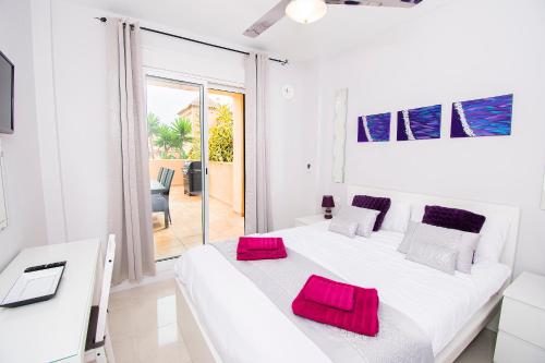 um quarto branco com uma grande cama branca com almofadas vermelhas em Alta Loma Costa em Fuengirola