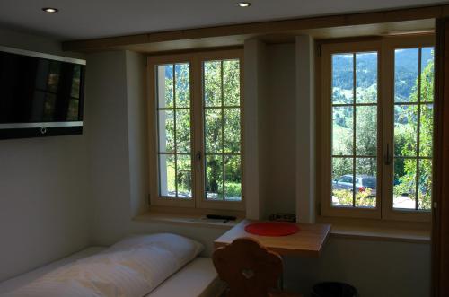 a room with three windows and a bed and a table at Ferienwohnung Uf dr Liwwi in Grindelwald