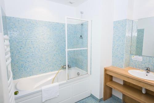 een badkamer met een bad en een wastafel bij Hôtel Le Chalet in Ax-les-Thermes