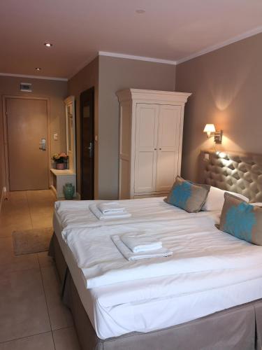 a bedroom with a large bed with white sheets and blue pillows at Riviera Resort Airport Modlin in Olszewnica Nowa