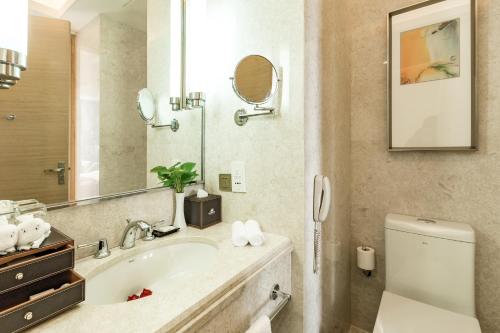 a bathroom with a sink and a toilet and a mirror at Maritim Hotel Changzhou in Changzhou