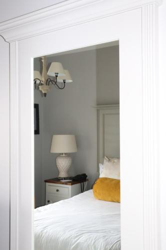 a bedroom with a white bed with a mirror at Causeway Hotel in Bushmills