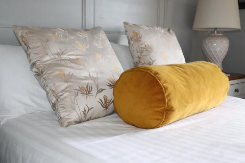 a yellow pillow sitting on a bed with two pillows at Causeway Hotel in Bushmills