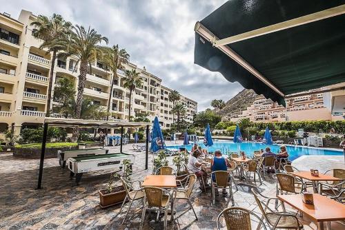 a group of people sitting at tables by a pool at Studio Castle Harbour vistas piscina in Los Cristianos