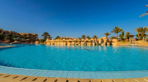 a large swimming pool in a resort with palm trees at Blend Elphistone Resort Marsa Alam in Abu Dabab