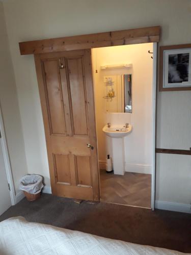 a bathroom with a door leading to a sink at Bryn Elltyd Eco House in Blaenau-Ffestiniog