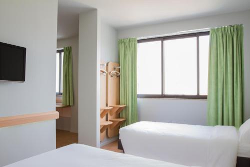 Una habitación de hotel con dos camas y una ventana. en Ibis Budget Braga Centro, en Braga
