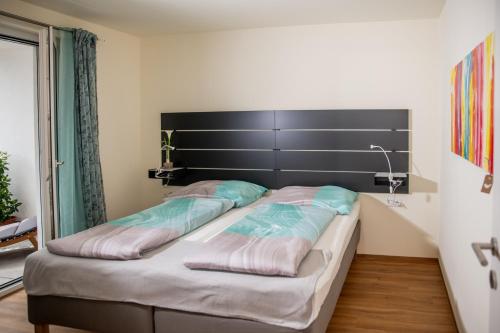 a bedroom with a large bed with a black headboard at Cityapartment Dornbirn 50 qm in Dornbirn