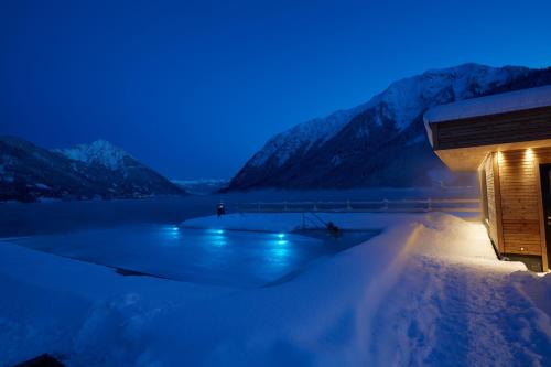 a house in the snow at night with mountains at Entners am See in Pertisau