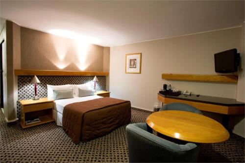 Habitación de hotel con cama y mesa en President Hotel en Bloemfontein