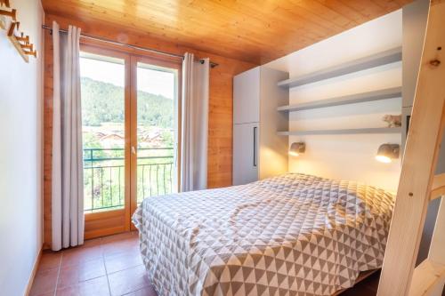 une chambre avec un lit et une grande fenêtre dans l'établissement Les Brebis, à Morzine