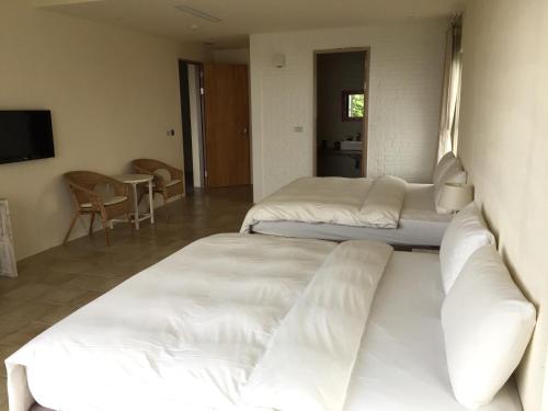 a hotel room with three beds and a television at Seashore My Home in Eluan
