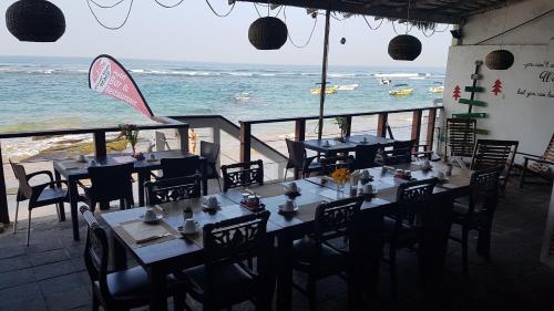 a restaurant with tables and chairs and the ocean at Coral Seas Beach Hikkaduwa in Hikkaduwa